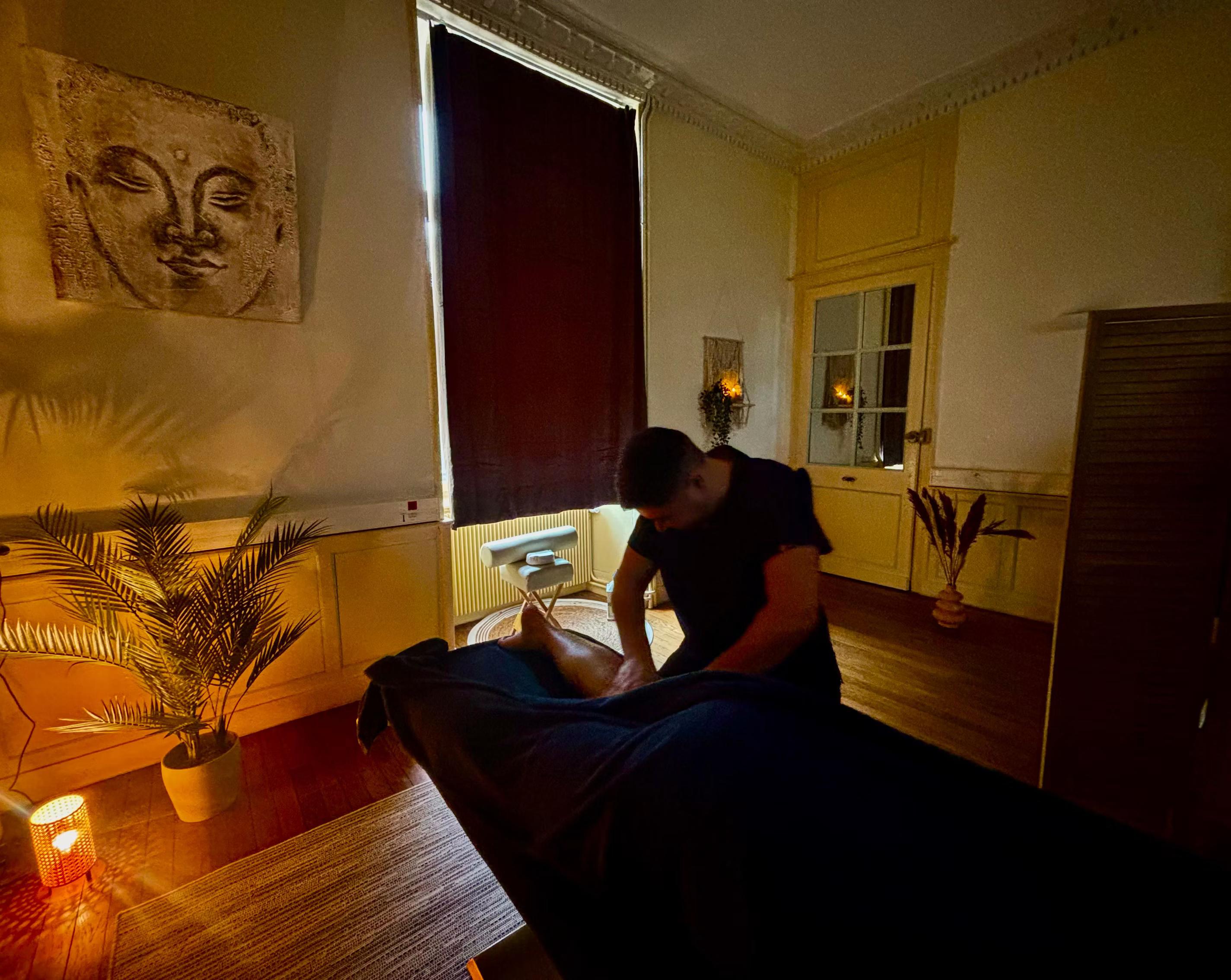 Massage des jambes dans une salle tamisée du spa MCH, avec tableau de Bouddha, palmier et bougies