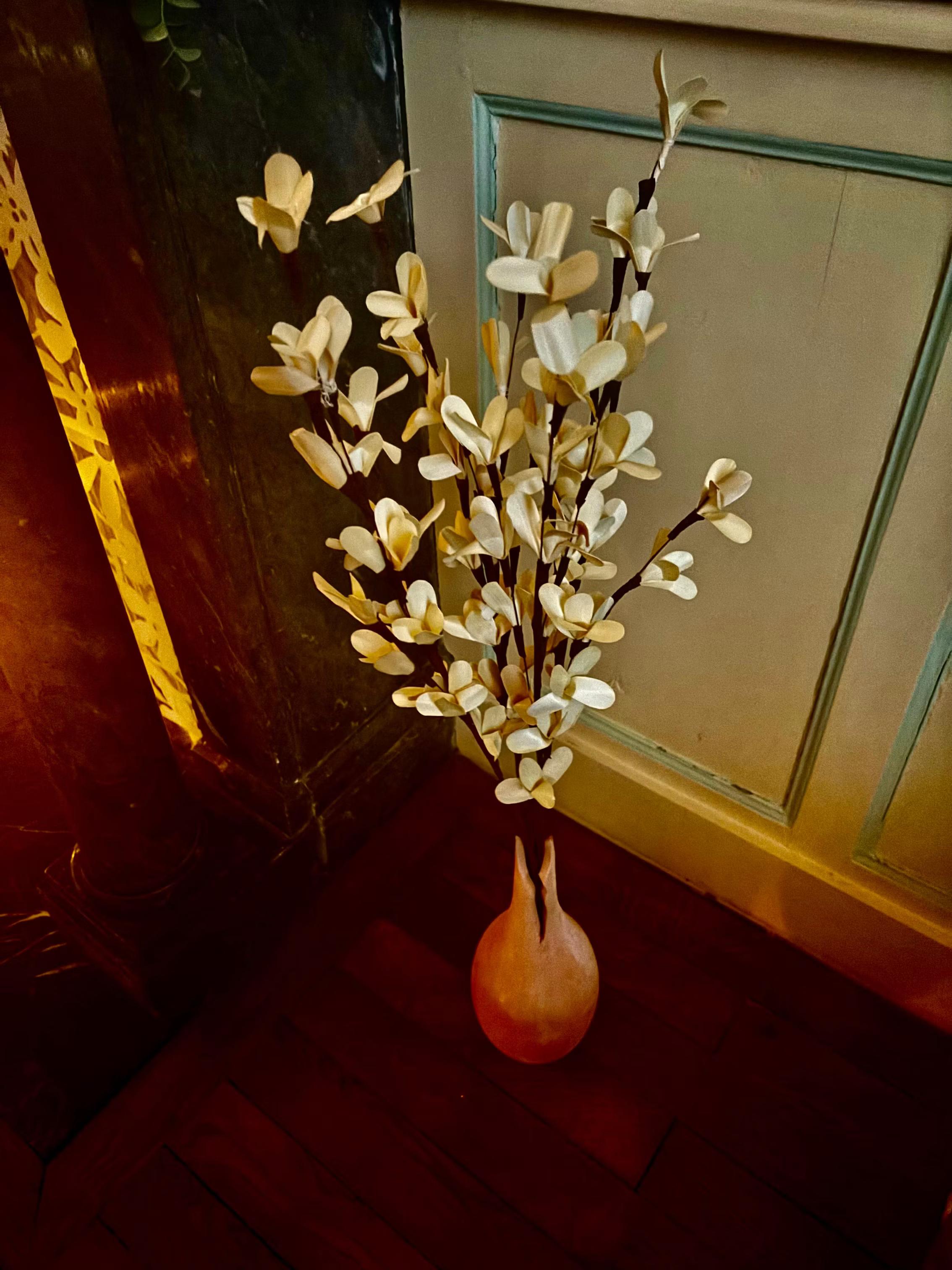 Bouquet de fleurs crème dans un vase en terre cuite sur le parquet, décor tamisé du spa MCH