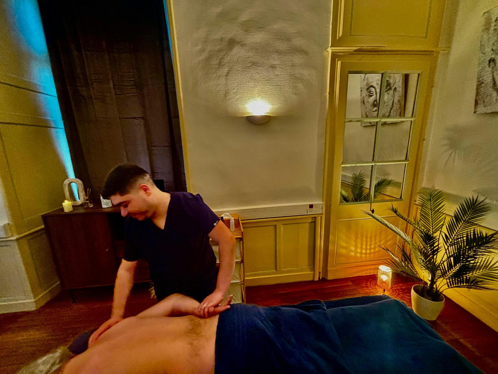 Massage du dos d'un client allongé sur le ventre, dans une salle tamisée du spa MCH