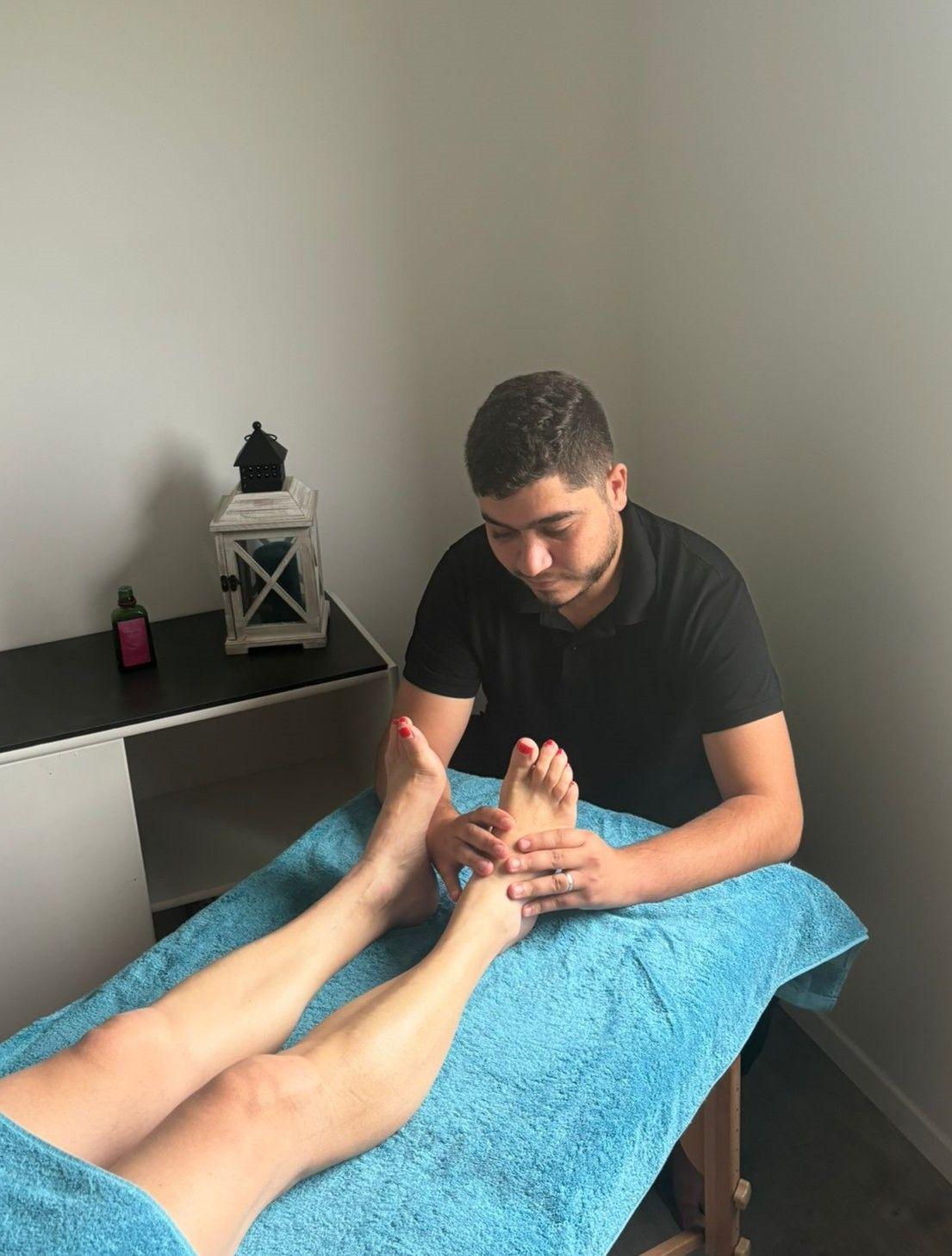 Massage des pieds d'une cliente allongée sur une serviette turquoise, spa MCH